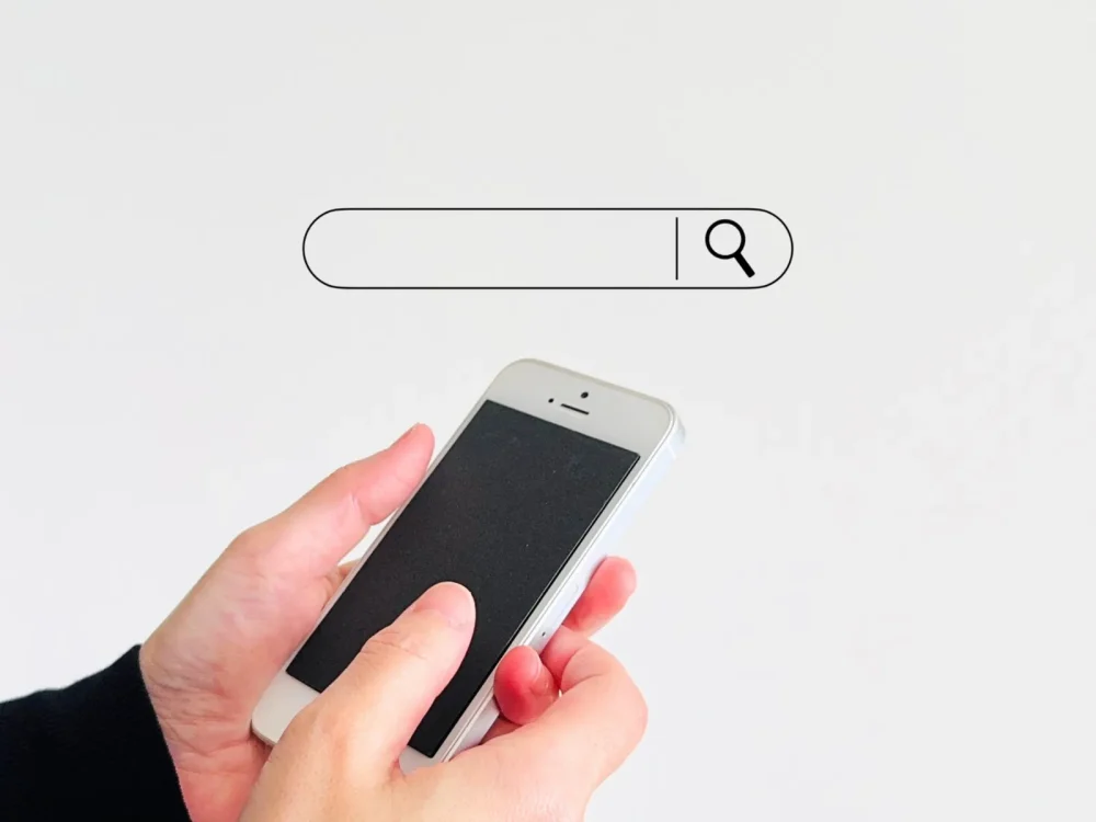 スマートフォンで検索バーを操作する手元