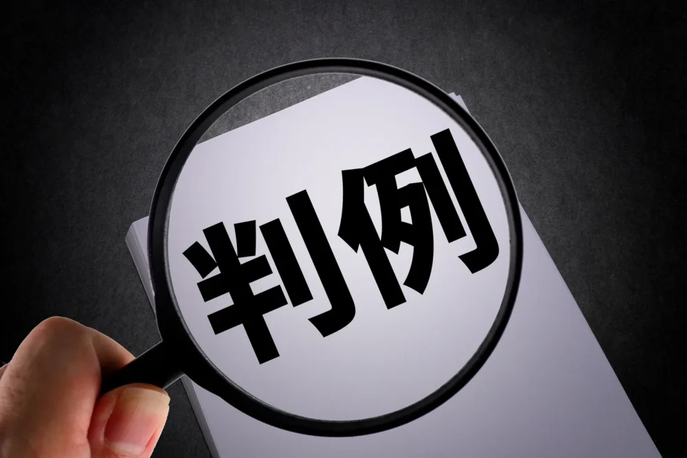 「判例」と書かれた紙を虫眼鏡で見る手元